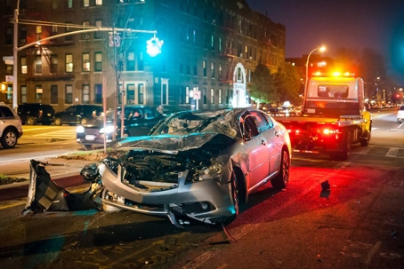 tow truck behind a smashed grey sedan at an accident scene
