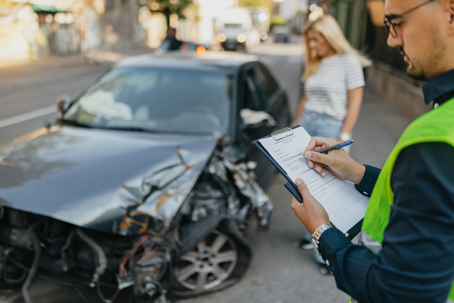 insurance agent examines damaged car