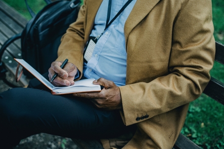 person with notebook sitting on bench