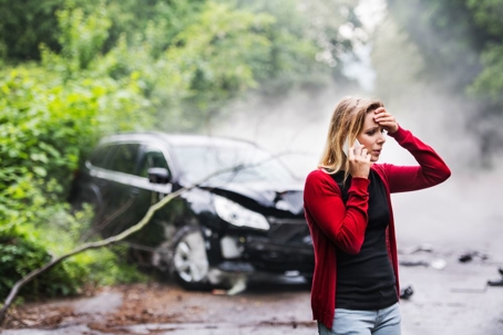 woman on phone in front of crashed car